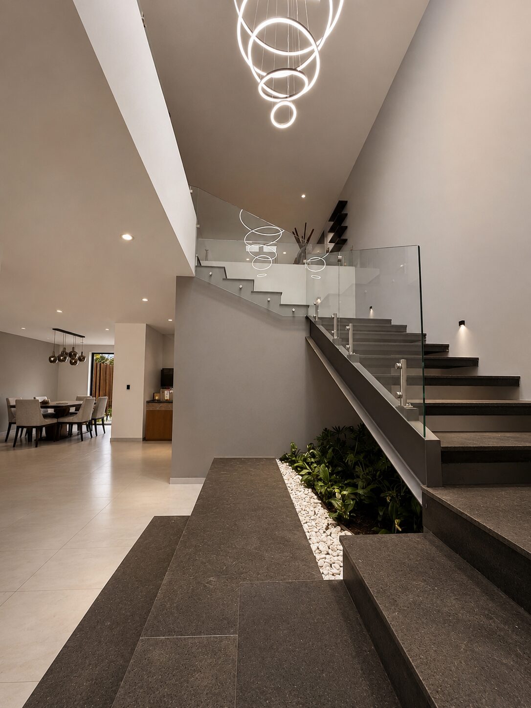 Double-height entrance hall with staircase and indoor planter · Casa Britania, Morelia