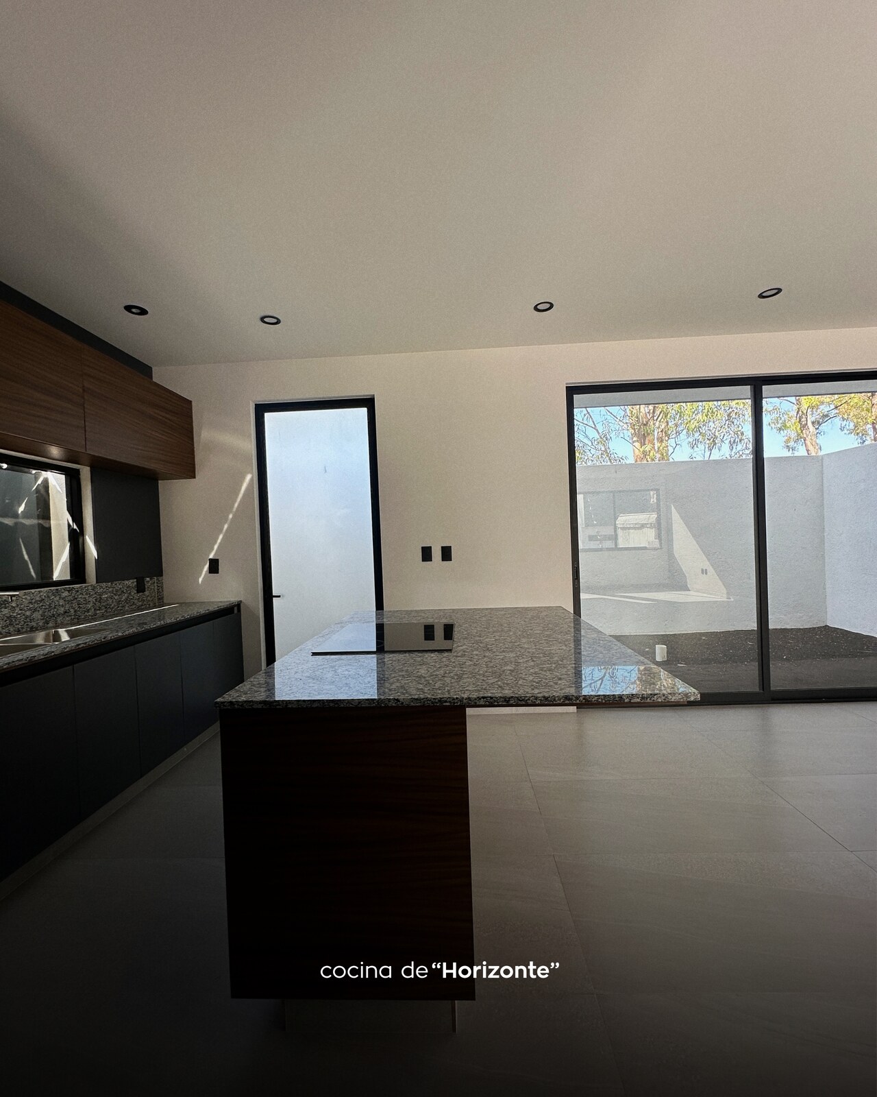 Cocina abierta con ventanal corredizo al jardín · Casa Horizonte por Mircon Constructora