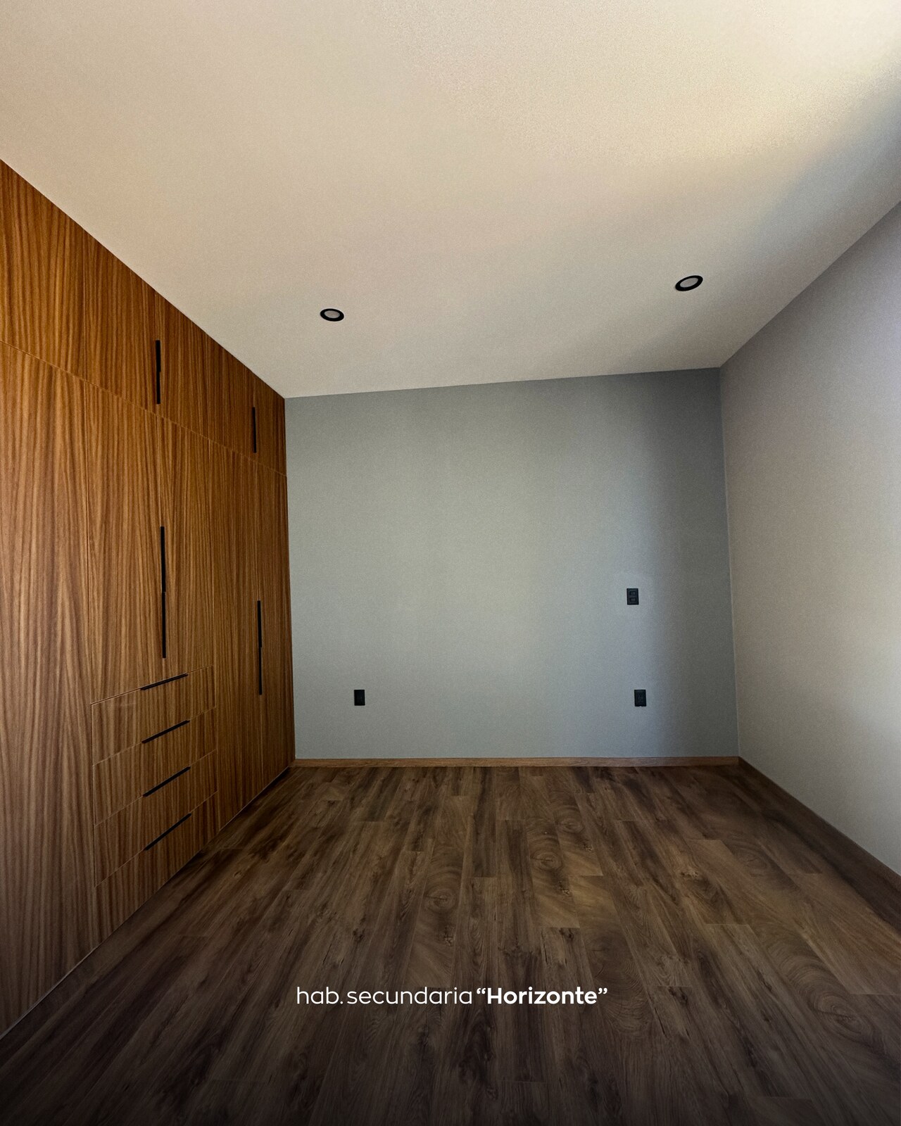 Habitación secundaria con closet de madera y pared gris · Casa Horizonte por Mircon Constructora