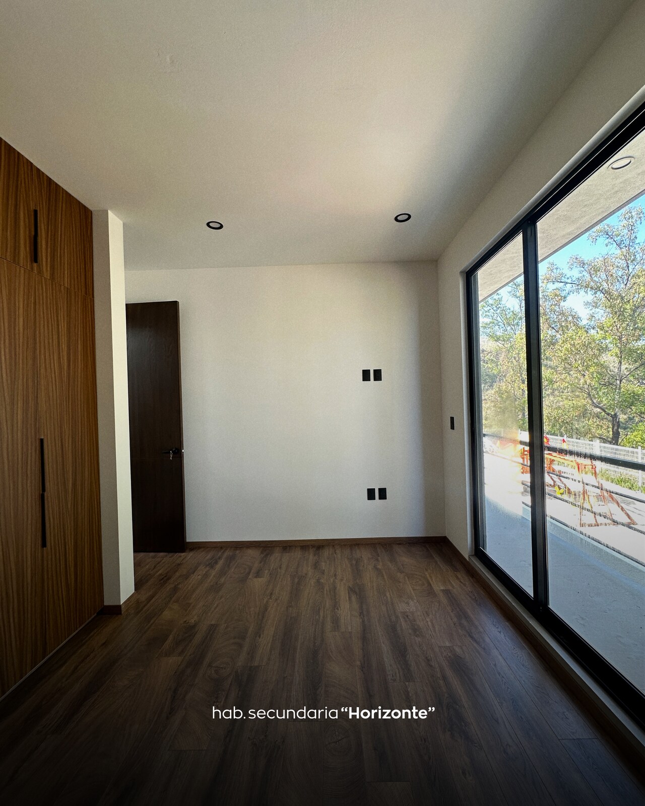 Habitación secundaria con closet de madera y ventanal corredizo al balcón · Casa Horizonte