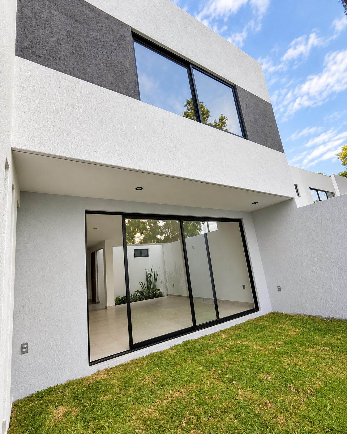 Rear facade with sliding window and garden · Casa Magna by Mircon Constructora, builders in Morelia