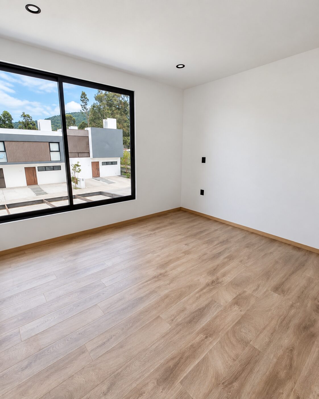 Bedroom with large window and wood-look floor · Casa Magna, Mircon builders in Morelia
